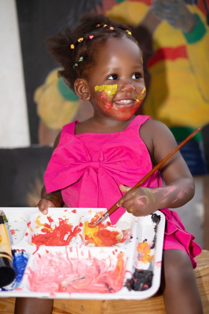 Little girl enjoying a creative painting session, cheerful and artistic.